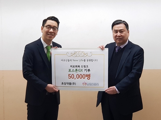 김우석 초당약품 상무(좌)가 탁우상 서울시립서대문노인종합복지관 관장(우)에게 피로회복음료 ‘포스톤 GX’ 5만 병을 전달하고 있다. /사진=초당약품
