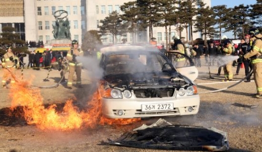 1일 국회 앞에서 국회의원 특권 폐지를 주장하며 분신을 시도한 남성의 자동차의 불을 끄고 있는 소방관. /사진=뉴시스