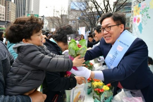 이대훈 NH농협은행장(오른쪽)이 14일 서울 광화문 일대에서 한 어린이에게 화분을 건네고 있다./사진=농협은행 제공