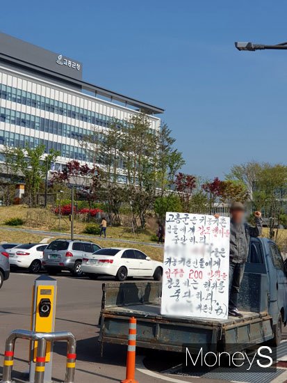 지난 22일 새터민 출신 귀촌인 A씨가 고흥군청 앞에서 '고흥군은 입주금 200만원을 강요하는 행위를 중단하라'며 손팻말을 들고 1인시위를 하고 있다. /사진제공=독자