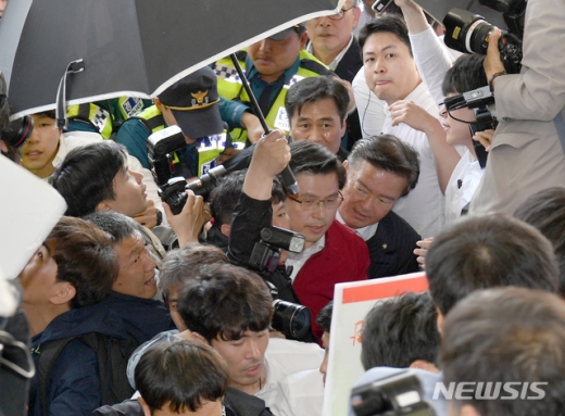 황교안 자유한국당 대표가 3일 오전 광주 광산구 송정역에서 규탄 대회를 마친 뒤 열차로 향하고 있다. 이 과정에서 물세례가 날아들자 경호인력이 우산을 들었다. /사진=뉴시스