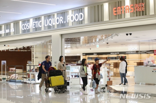 28일 인천공항 제2여객터미널 입국장에서 가족들이 입국장면세점 ‘엔타스듀티프리’ 개장 준비 모습을 바라보고 있다. /사진=뉴시스