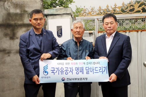 최근 김산 무안군수(사진 오른쪽 1번째)가 나형언 국가유공자 자택(일로읍 두레미 마을)을 방문해 대문에 국가유공자 명패를 직접 부착하며 공로를 치하했다. /사진제공= 무안군