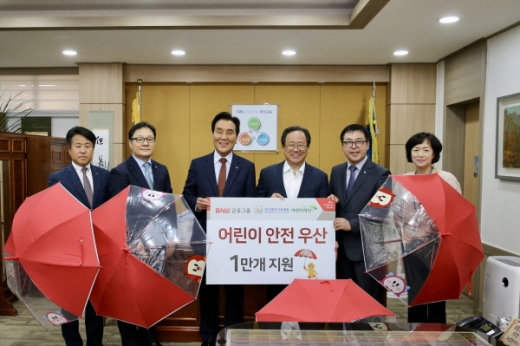 BNK금융그룹이 6월28일 ‘어린이 안전 우산’ 1만개를 부산시교육청에 기증했다. (왼쪽에서 세번째부터 BNK금융그룹 김지완 회장, 부산시 교육청 김석준 교육감, 초록우산 어린이재단 여승수 부산지역본부장)./사진제공=부산은행 