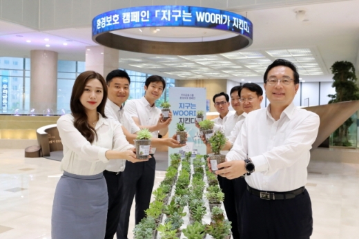 손태승(오른쪽) 우리금융그룹 회장 겸 우리은행장이 22일 임원진과 함께 본점 로비에서 플라스틱 컵을 재활용한 화분을 출근길 직원들에게 나눠주는 행사를 가진 뒤 기념촬영을 하고 있다./사진=우리금융