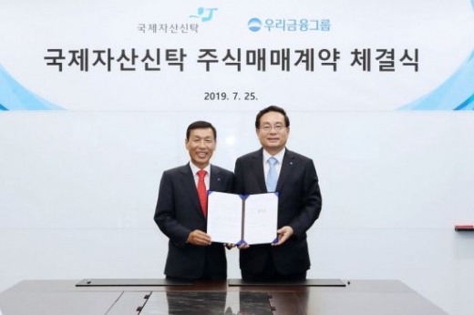 우리금융은 지난 25일 서울 종로구 법무법인 세종 회의실에서 국제자산신탁 경영권 지분 인수를 위한 SPA(주식매매계약)를 체결했다. 손태승 우리금융그룹 회장(오른쪽)과 유재은 국제자산신탁 회장이 기념촬영을 하고 있다./사진제공=우리금융