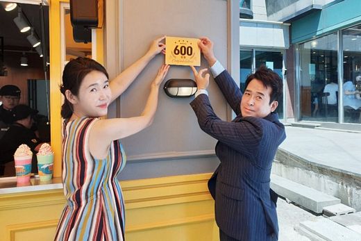 /성산일출봉점 한지안 점주와 메가커피 하형운 대표가 600호점 현판을 부착하고 있다.