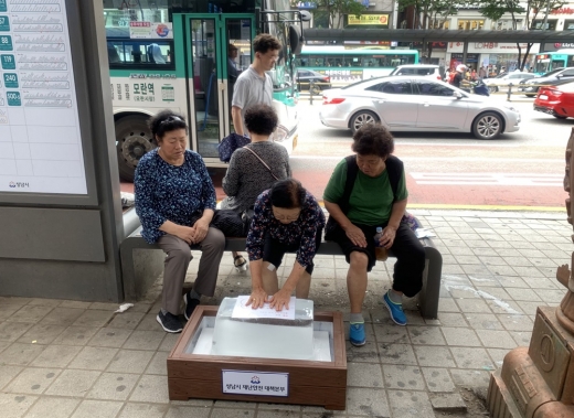 성남시민이 모란역 버스정류장에 비치한 얼음에 손을 올려놓고서 더위를 식히는 중이다. / 사진제공=성남시