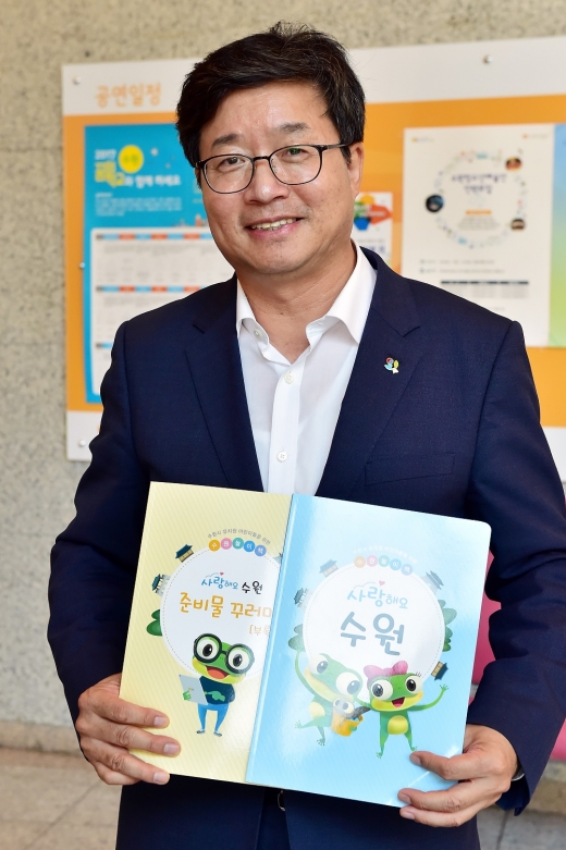 유치원용 ‘사랑해요 수원’ 교재를 들고 있는 염태영 수원시장. / 사진제공=수원시