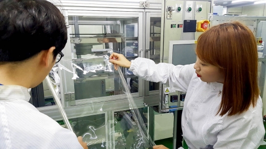 코오롱인더스트리 연구원들이 세계 최초로 개발한 투명 폴리이미드 필름(CPI®)을 점검하고 있다. / 사진=코오롱인더스트리