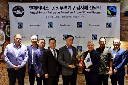/지난 11일 엔제리너스 석촌호수점에서 롯데GRS 남익우 대표(오른쪽 4번째)가 국제 공정무역기구 커피 최고 책임자 피터 캐틀러(Peter Kettler)로부터 감사패를 전달 받고 기념촬영을 하고 있다 (사진제공=엔제리너스)