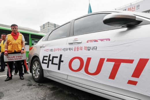 지난 6월19일 서울 종로구 KT 광화문빌딩 앞에서 열린 ‘타다 서비스 중단 촉구 집회’에서 서울개인택시운송조합 조합원들이 택시 우측 면에 ‘타다 OUT!’이 적힌 현수막을 부착해 놓고 있다. / 사진=뉴스1 민경석 기자