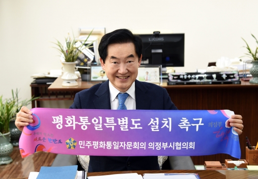 안병용 의정부시장이 18일 민주평화통일자문회의 의정부시협의회(회장 윤상용)에 참석해 '민주평통 평화통일특별도 설치 촉구' 플랭카드를 펼쳐 보이고 있다. / 사진제공=의정부시