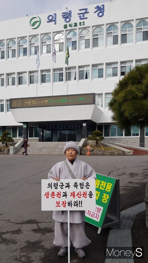 경남 의령군 용덕면 소재 원각사 주지 원각스님(58)이 지난 3일부터 “의령군과 의령축협은 생존권과 재산권을 보장하라!”는 손피켓을 들고 의령군청 앞 광장에서 27일째 1인 시위를 이어오고 있다. &copy;임승제 기자.